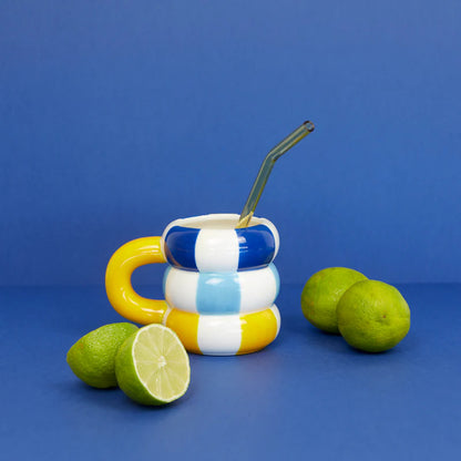 Floats Gialla mug with a straw and two halved limes on a blue background