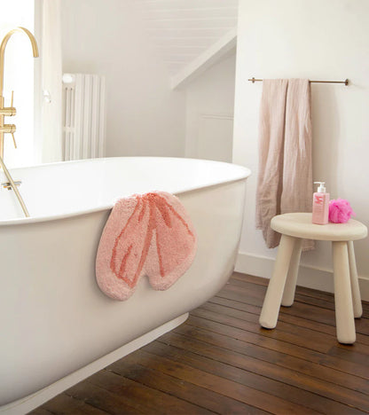 Soft bow rug in pink draped over the edge of a white bathtub