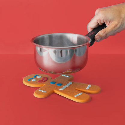 Ginger Man trivet with a metal saucepan held above it, on a red background.