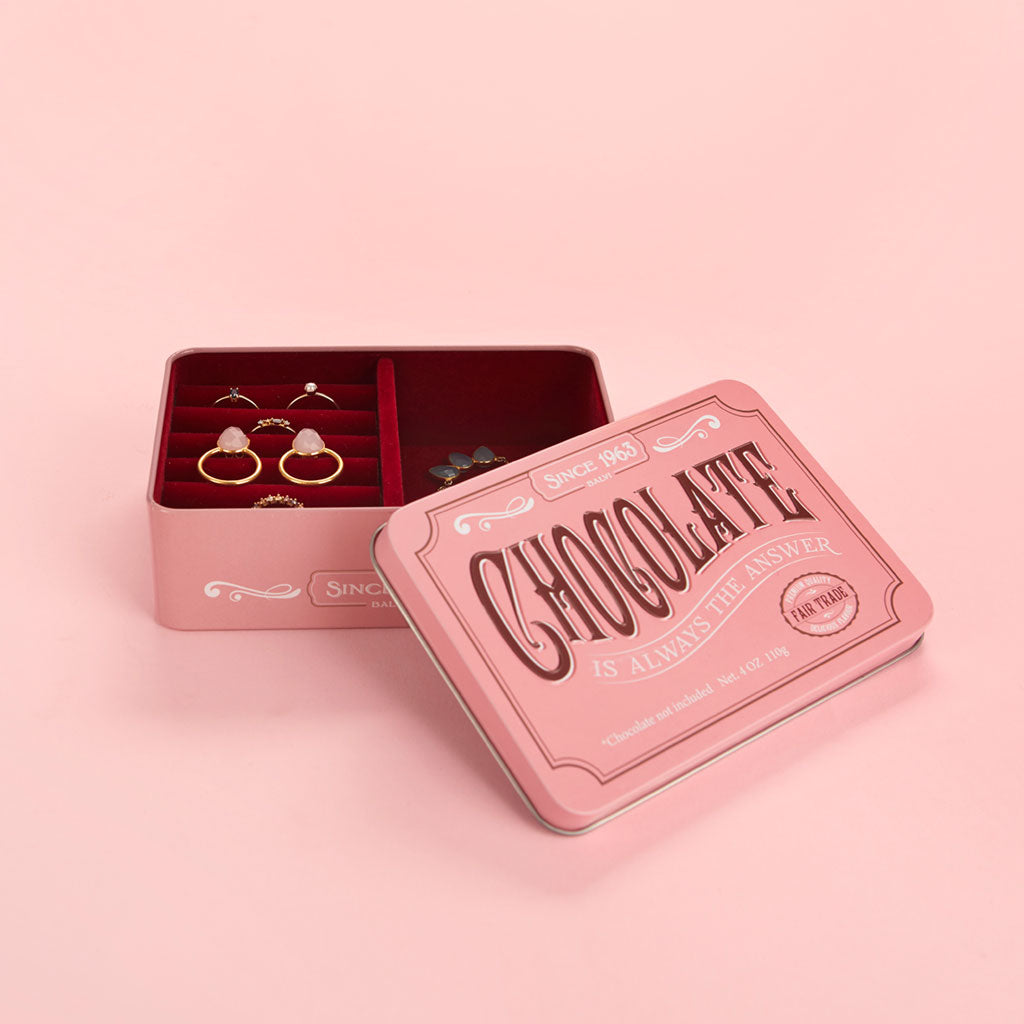 Portagioie Chocolate su sfondo rosa, aperto con anelli e una collana visibili