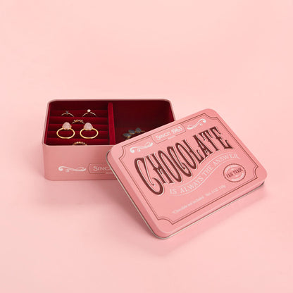Portagioie Chocolate su sfondo rosa, aperto con anelli e una collana visibili