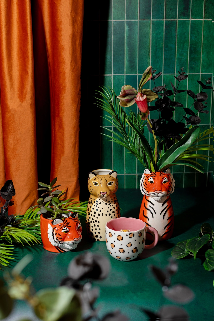 Tiger vase with palm leaves next to a mug and a leopard-shaped vase