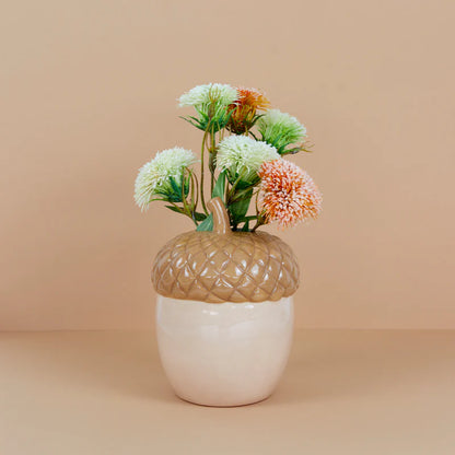Acorn vase with the same flowers, photographed against a beige background.