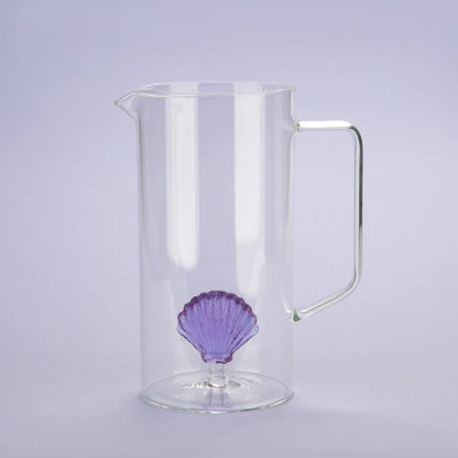 Atlantis jug in clear glass with the purple shell, photographed against a lilac background.