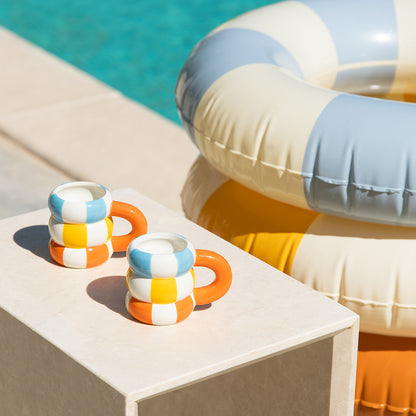Float cup set poolside with two inflatable rings in the background