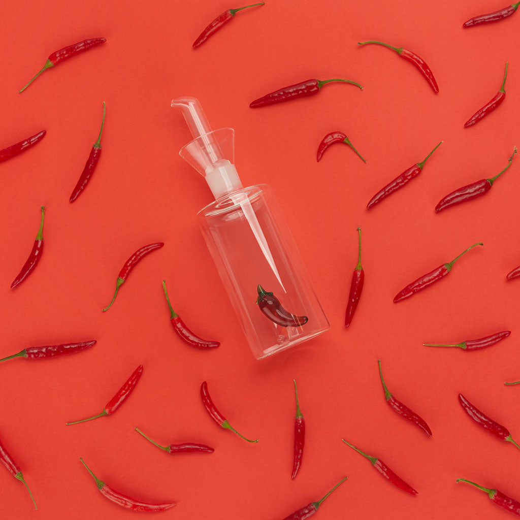 Oliera Chilli: il beccuccio dell'oliera visto dall'alto, tra peperoncini sparsi sul rosso.