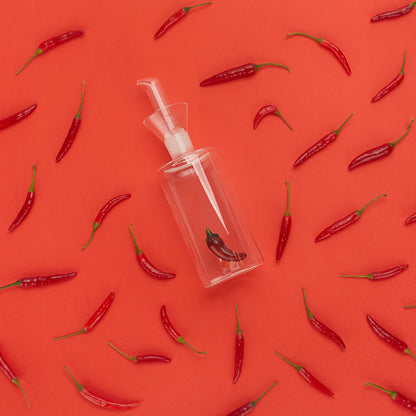 Oliera Chilli: il beccuccio dell'oliera visto dall'alto, tra peperoncini sparsi sul rosso.