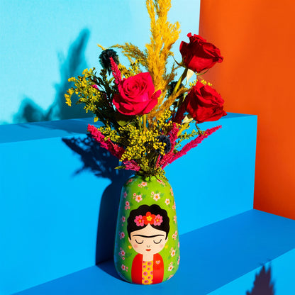 Vaso Frida Floral holding red roses and yellow blooms, set on blue and orange steps.
