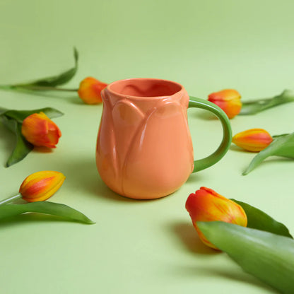 Orange Tulip mug on a green background surrounded by real tulips