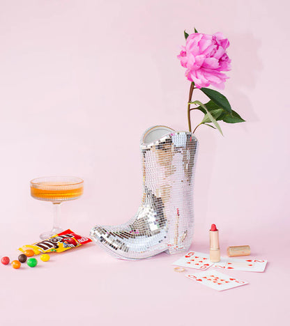 The mirrored boot vase with a pink peony, among sweets and playing cards