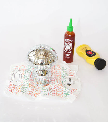 The mini gold mushroom lamp placed next to a bottle of hot sauce
