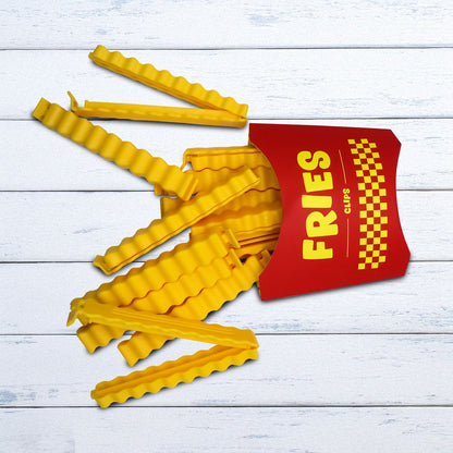 Fries food clips yellow clips scattered on a wooden table, next to the red fry-box packaging.
