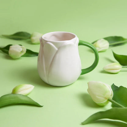 White Tulip mug on a green background surrounded by white tulips