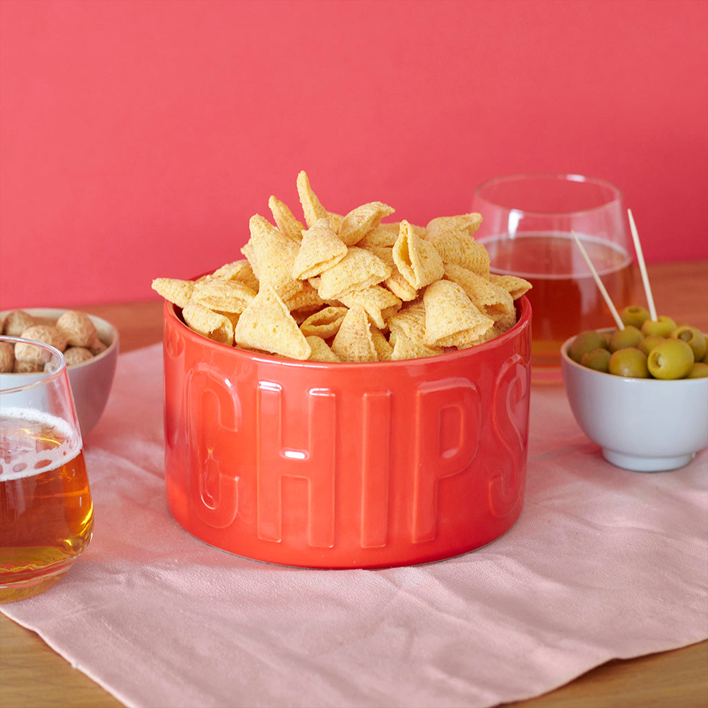 Ciotola Snack Chips rossa piena di nachos, tra un bicchiere di birra e una ciotola di olive