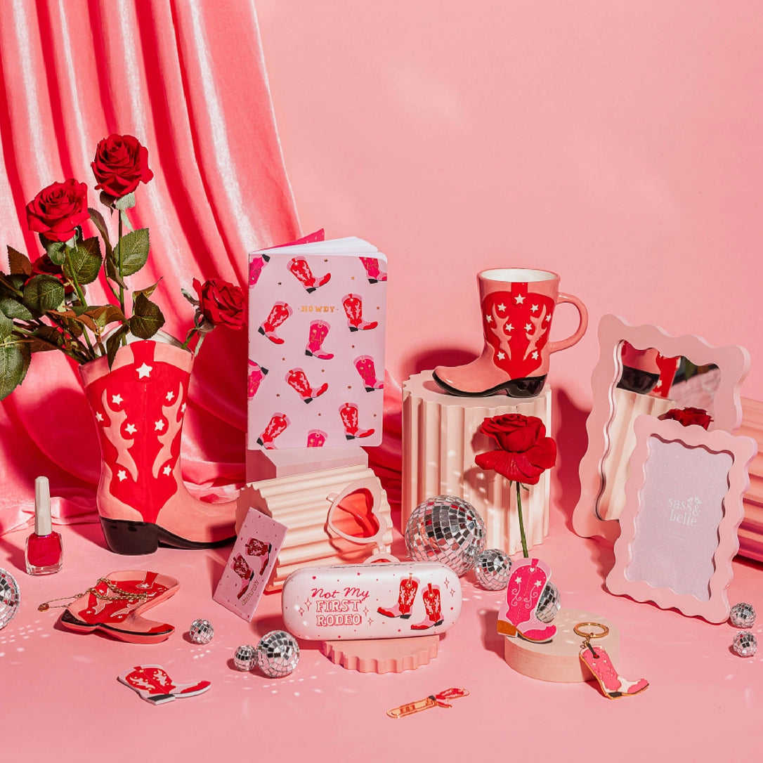 The Rodeo mug styled in a pink cowgirl-themed set, with boots, roses and disco balls.