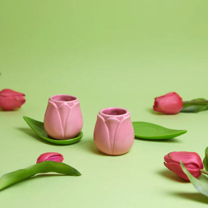 Tulip espresso cups on a green background, surrounded by real pink tulips