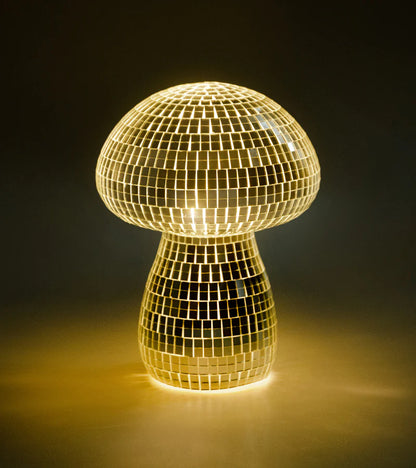 Mini version of the mirrored mushroom lamp in gold, lit in the dark
