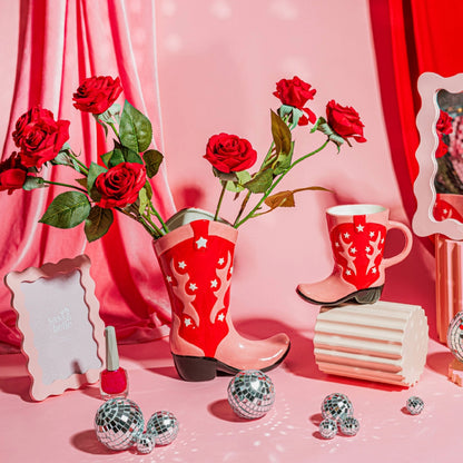 Rodeo mug shaped like a red cowboy boot with white stars, next to the matching vase.