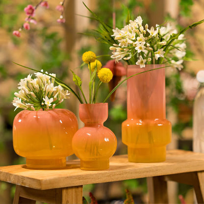 Glow vase in ombre glass, styled with two other vases from the same line and flowers, on a wooden table.