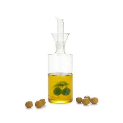 Olive oil cruet filled with oil, real olives around it, on a white background