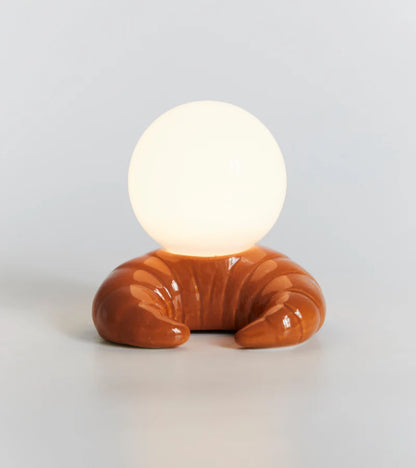 Croissant-shaped ceramic lamp with a glowing white sphere on top