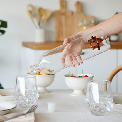 Atlantis Corallo bottle being tilted by a hand to pour water at the table