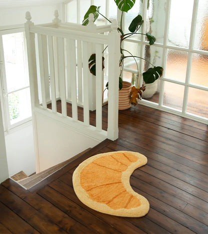 Croissant rug in honey tone on the floor in front of dark wooden kitchen units
