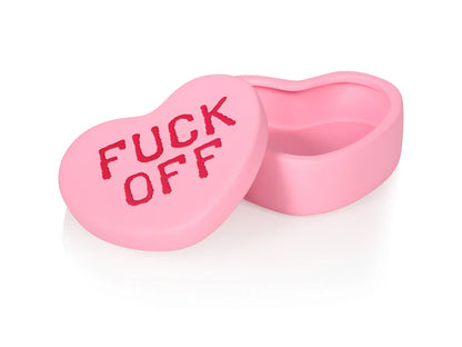 Fuck Off heart box in pink, open on a dressing table among perfumes and a mirror.