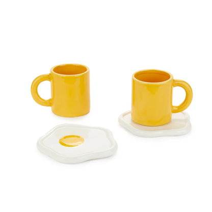 Sunny Side Up coffee cup set: two yellow mugs with white saucers shaped like fried eggs.