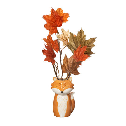 Vaso Volpe Finley orange and white fox-shaped vase, filled with artificial autumn leaves.