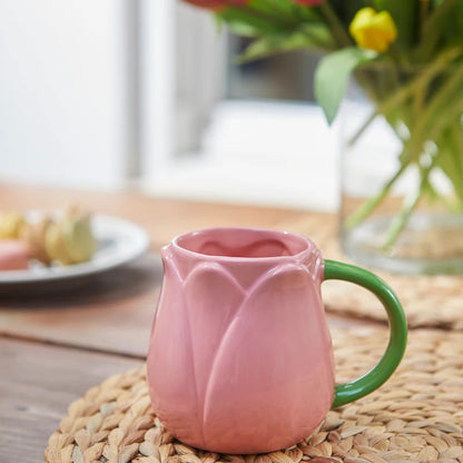 Pink Tulip mug on a wooden table with biscuits and a vase of flowers in the background