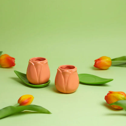 Orange Tulip coffee cup set with leaf-shaped saucers on a green background among tulips
