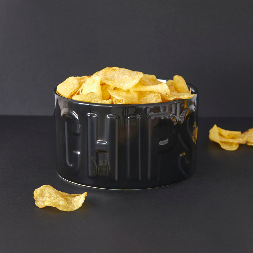 Ciotola Snack Chips nera piena di patatine, con alcune sparse sullo sfondo nero