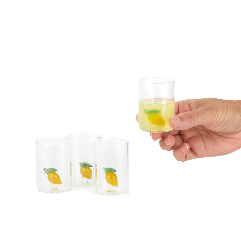 Lemon Shot Glass Set: a hand holding one full glass next to the other empty ones.