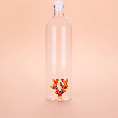 Atlantis Corallo bottle, clear glass with an orange coral shape at the base, peach background