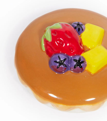 Pancake mug, close-up on the lid with a decorative strawberry, blueberries and mango