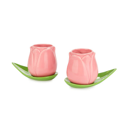 Two pink tulip-shaped espresso cups with a green leaf-shaped saucer, on white
