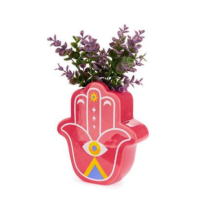 Pink hamsa-hand-shaped vase, holding a purple plant