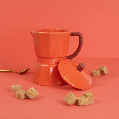 Orange Moka mug on a red background with a gold spoon and brown sugar