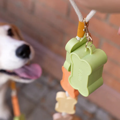 Green Biscuit dog waste bag holder, closed with the bag poking out, white background