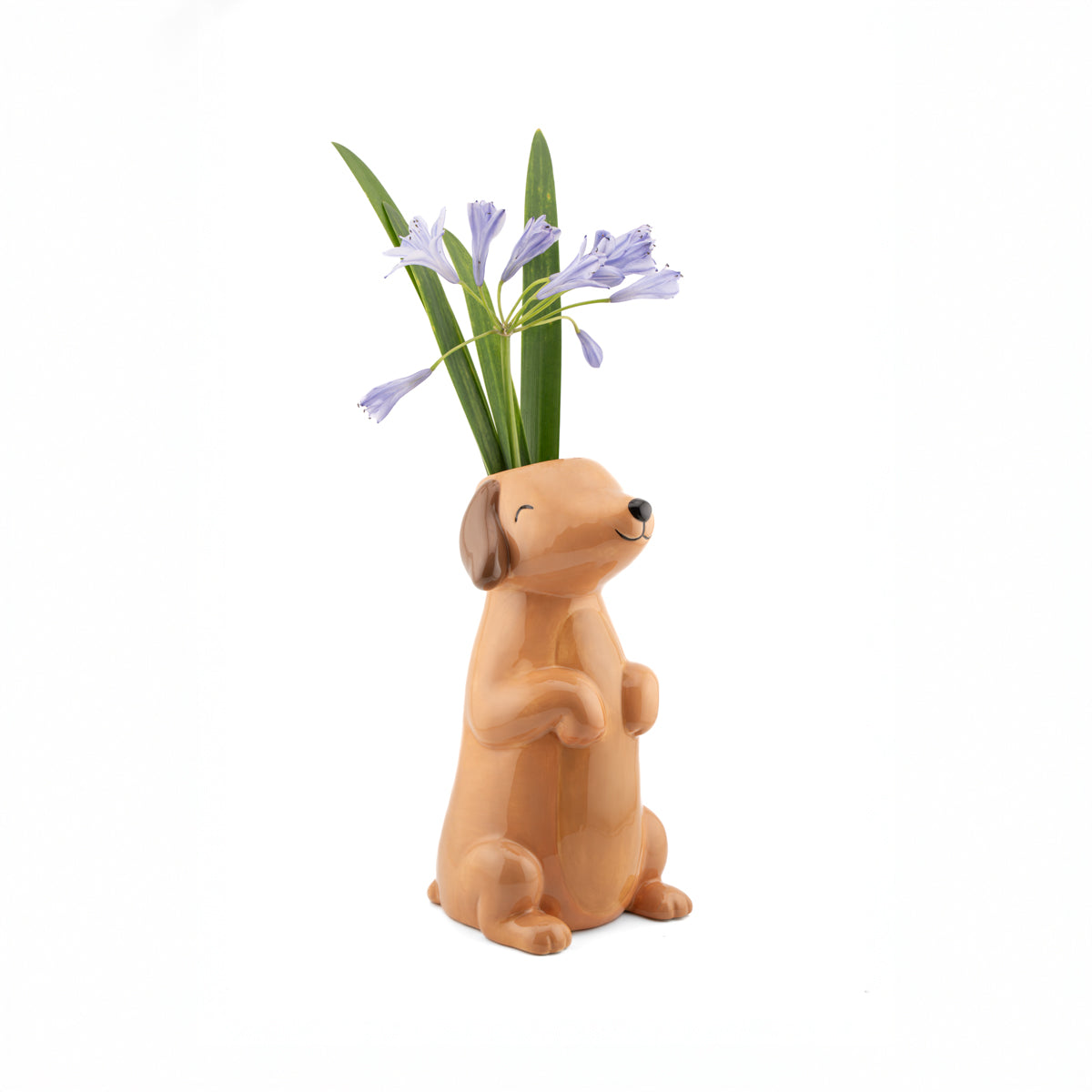 The Bassotto vase with a bunch of purple flowers arranged in the opening behind its head.