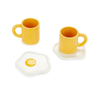 Sunny Side Up coffee cup set two yellow mugs and two egg-shaped saucers on a white background.