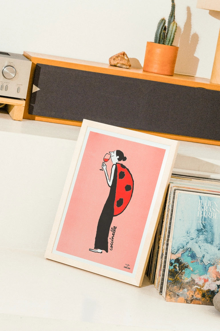 Poster Ladybug: stesso poster appoggiato su una mensola vicino a un disco e una pianta grassa