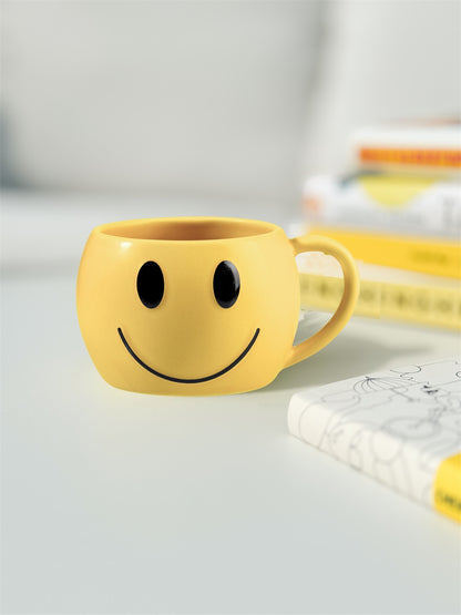 Mood mug, yellow cup on a white table next to a stack of books