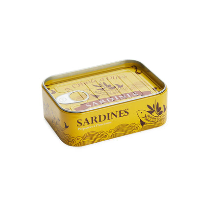 Conserverie Sardines a hand lifting a fish-bone shaped fork from a board, near the open yellow tin.