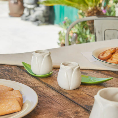 Tulip Coffee Cup Set: the white cups on a wooden breakfast table with bread and plates.