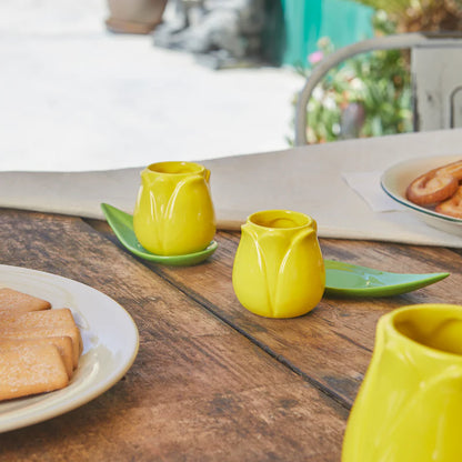 Tulip Coffee Cup Set: the yellow cups on a wooden table set for breakfast outdoors.