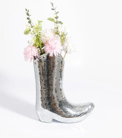 Boot-shaped vase covered in silver mirror tiles, holding pink flowers