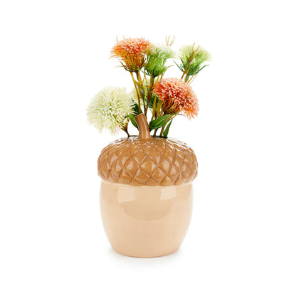 Acorn vase in tan and cream, holding dried orange and cream flowers on top.
