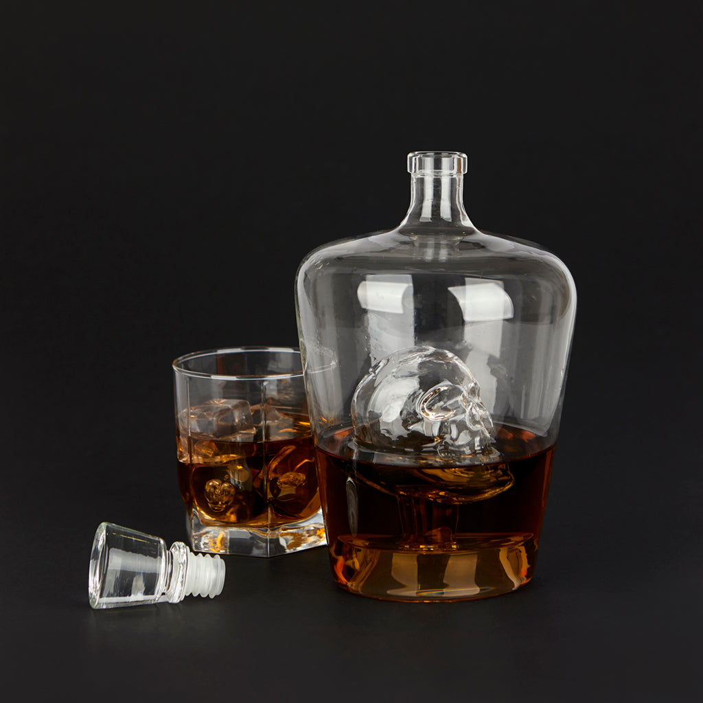 Poison Bottle: the decanter with the skull inside, filled with whisky, black background.